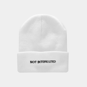 Close-up of NOT INTERESTED embroidery on white cuffed knit beanie hat with texture
