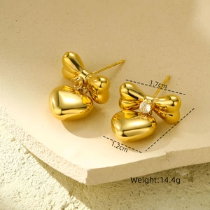 Macro detail of gold bow and heart earrings with white crystals on stone base