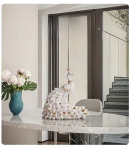Detailed peacock statue on marble table with golden feather accents and blue vase decor