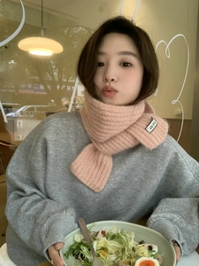 Detailed close-up of a pink knitted scarf featuring a KN STU brand tag on a model