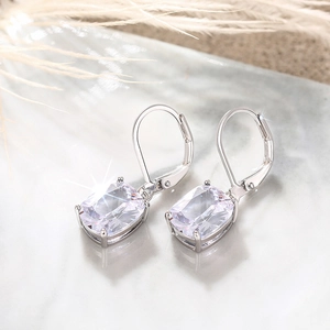 Detail of silver lever-back earrings with cushion-cut clear stones on marble surface