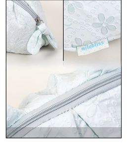 Detail of light blue embroidered pouch with metal zipper and fabric bow decoration