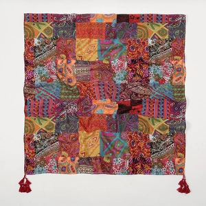 Close-up of bohemian scarf with red tassels and paisley print on cotton-linen fabric