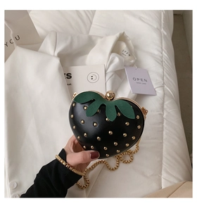 Detailed close-up of a black strawberry shaped mini bag with gold studs and a chain strap