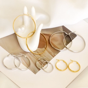 Minimalist large stainless steel hoop earrings in gold and silver set on a model hand