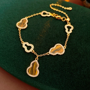 Macro detail of gold wulu charms with inlaid zircon and tiger eye on a green velvet mat