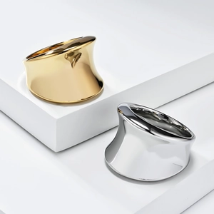 Detailed view of wide sculptural gold and silver rings with high-polish mirror finish