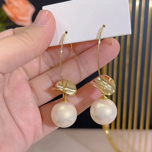 Elegant gold earrings with wave accents and large pearls on a stylish long curved hook
