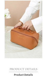 Detail showing the brown faux leather cosmetic bag with top handle and golden text logo
