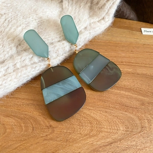 Macro detail of acetate resin earrings with geometric mosaic patterns on a wood surface
