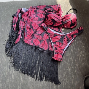 Detailed view of three-piece tropical leaf print swimwear set with black mesh tassel sarong