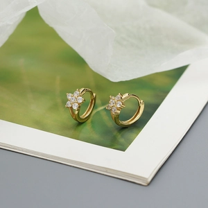 Close-up of gold-plated flower cluster hoop earrings with sparkling crystal accents