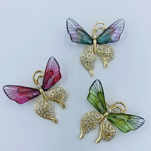 Three colorful butterfly brooches with gold wings and crystals on white background