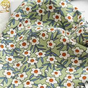 Gros plan d'un tissu floral avec de petites pâquerettes blanches sur un fond vert doux