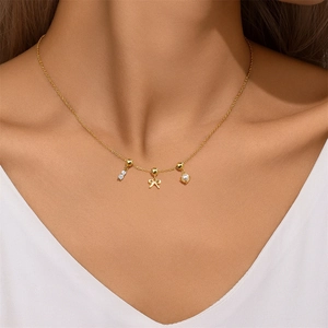 Close-up of golden necklace with bow, pearl and zircon pendants worn by model