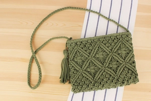 Detail of olive green macrame bag with fringe and intricate diamond woven texture