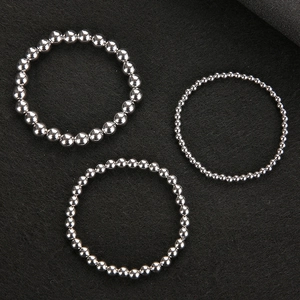 Three minimalist silver stainless steel bead rings of varying sizes on dark background