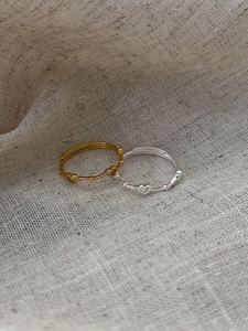 Detail of minimalist 925 silver open heart rings in gold and silver on linen fabric