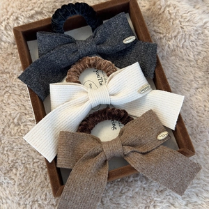 Three-piece set of knitted bow scrunchies in dark gray, cream, and camel soft fabric