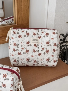 Detailed macro view of quilted corduroy makeup bag with red floral patterns and zipper