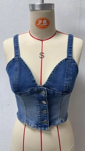 Detail view of v-neck denim vest with silver metal buttons and washed texture