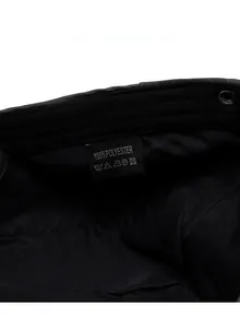 Care label detail showing 100% polyester material and washing icons on black fabric