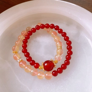 Détail de bracelets en agate rouge et cristal orange sur un plateau en marbre blanc