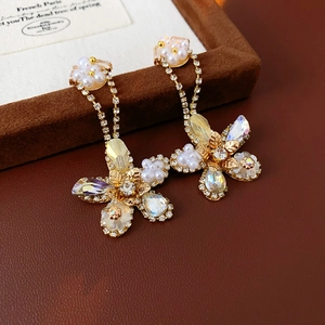 Detailed shot of gold floral drop earrings with white pearls and sparkling crystals
