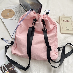 Flachbild eines rosa Kordelzug-Rucksacks mit Nylonriemen neben Büchern und Laptop