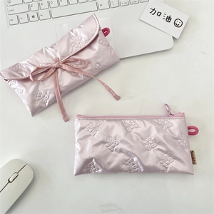 Gros plan de trousses roses matelassées avec texture papillon sur tissu satiné soyeux