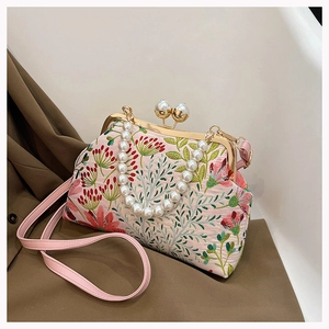 Detaillierte Stickerei mit Blumenmustern und Perlenverschluss an einer rosa Handtasche