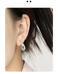 Close-up of silver S925 sterling silver U-shaped hoop earring with geometric cutouts