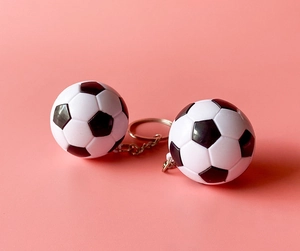 Gros plan de porte-clés football noir et blanc classiques sur un fond rose uni
