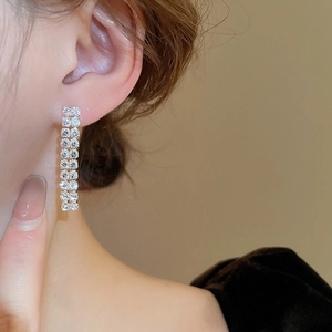 Close-up of silver zircon tassel earrings worn by a model in soft lighting