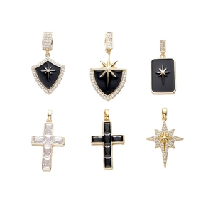 Gold shield and cross pendants with black enamel and zircon stones on white background