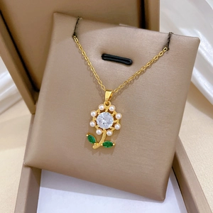 Detail view of a floral pearl necklace with green leaf accents in a premium jewelry box