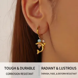 Detail of dolphin charm hoop earring with gold metal and light blue faceted beads