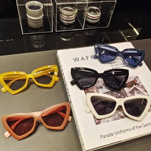 Five pairs of retro triangle cat-eye sunglasses arranged on a book in different colors