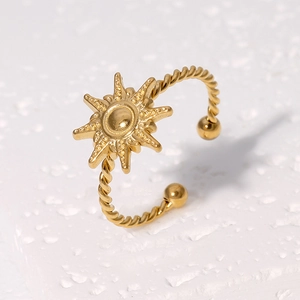 Detailed shot of a gold sunburst open ring with a twisted band on a white texture
