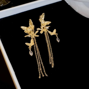 Detailed macro shot of golden double butterfly earrings with long metal tassel chains