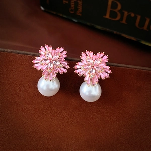 Macro view of flower zircon stud earrings with pink petals and white drop pearl detail