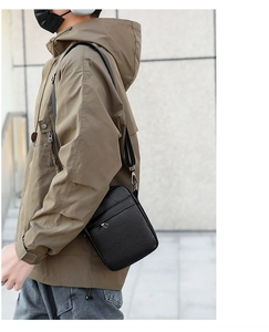 Detail of a men's black PU leather crossbody bag featuring a triangular metal logo decoration