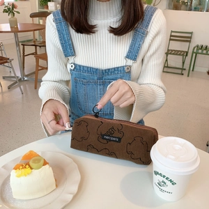 Détail de la trousse en velours côtelé marron avec motif d'ours et zip à anneau