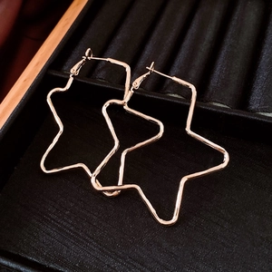 Close-up of star-shaped hoop earrings in rose gold finish on black velvet background