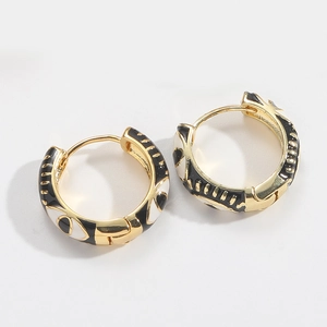 Detailed view of gold hoop earrings with black and white enamel eye patterns