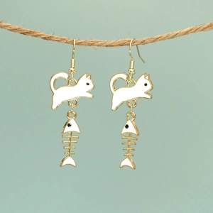 Creative gold cat and fishbone earrings hanging on jute rope with blue background