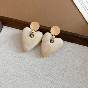 Detailed close-up of cream marble acrylic heart earrings with elegant gold chain links