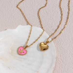 Golden heart pendant necklaces with pink cupid design on a seashell display base