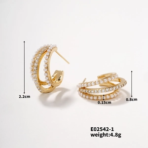 Détail de boucles d'oreilles C dorées de 2,2 cm avec perles et strass au design multicouche