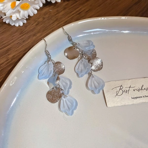 Detail of silver long drop earrings with blue shell petals on a ceramic tray